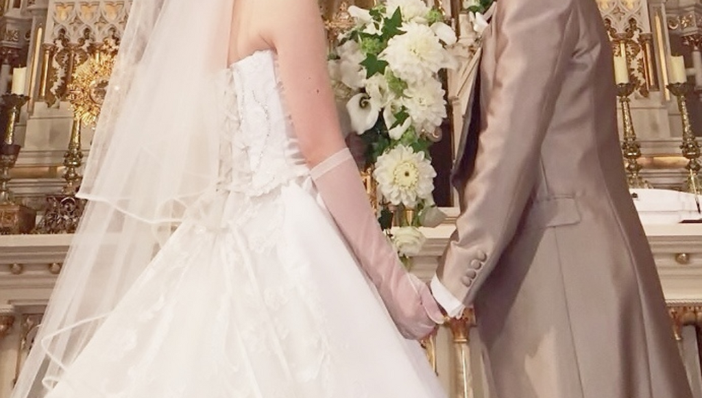 挙式で新郎と新婦が手を握ってる